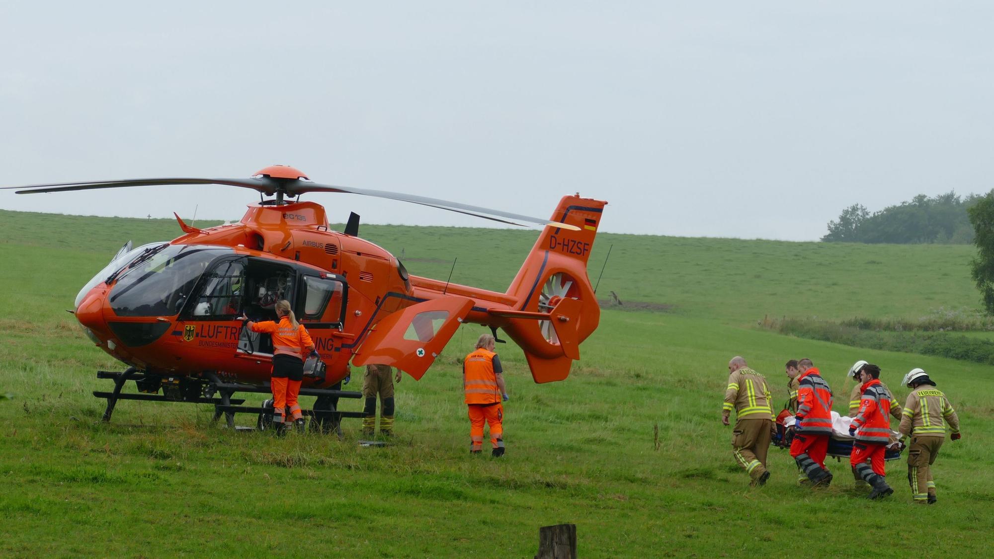 Feuerwehrleute tragen eine Patientin zu einem Rettungshubschrauber.