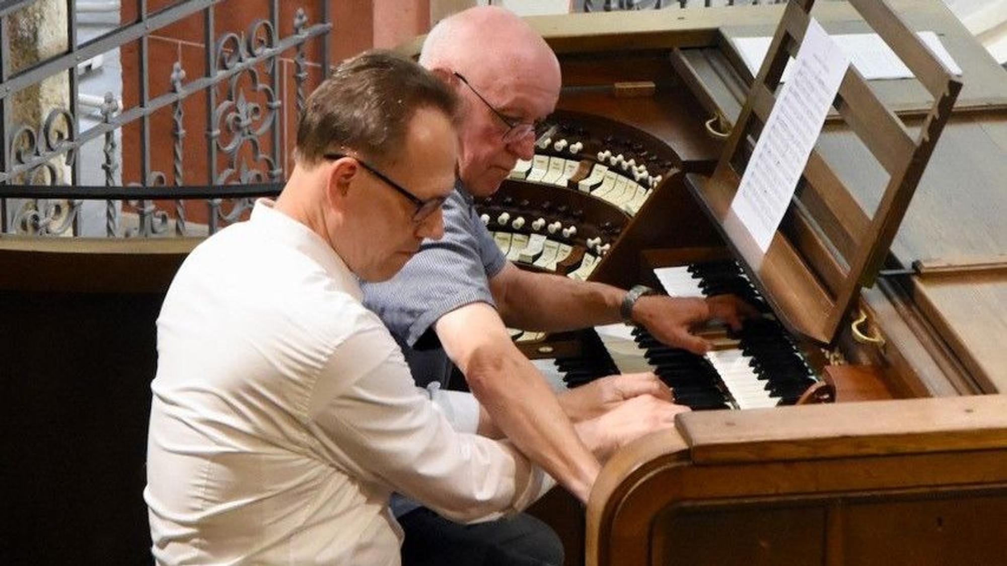 Zwei Männer spielen gemeinsam an einer Orgel.