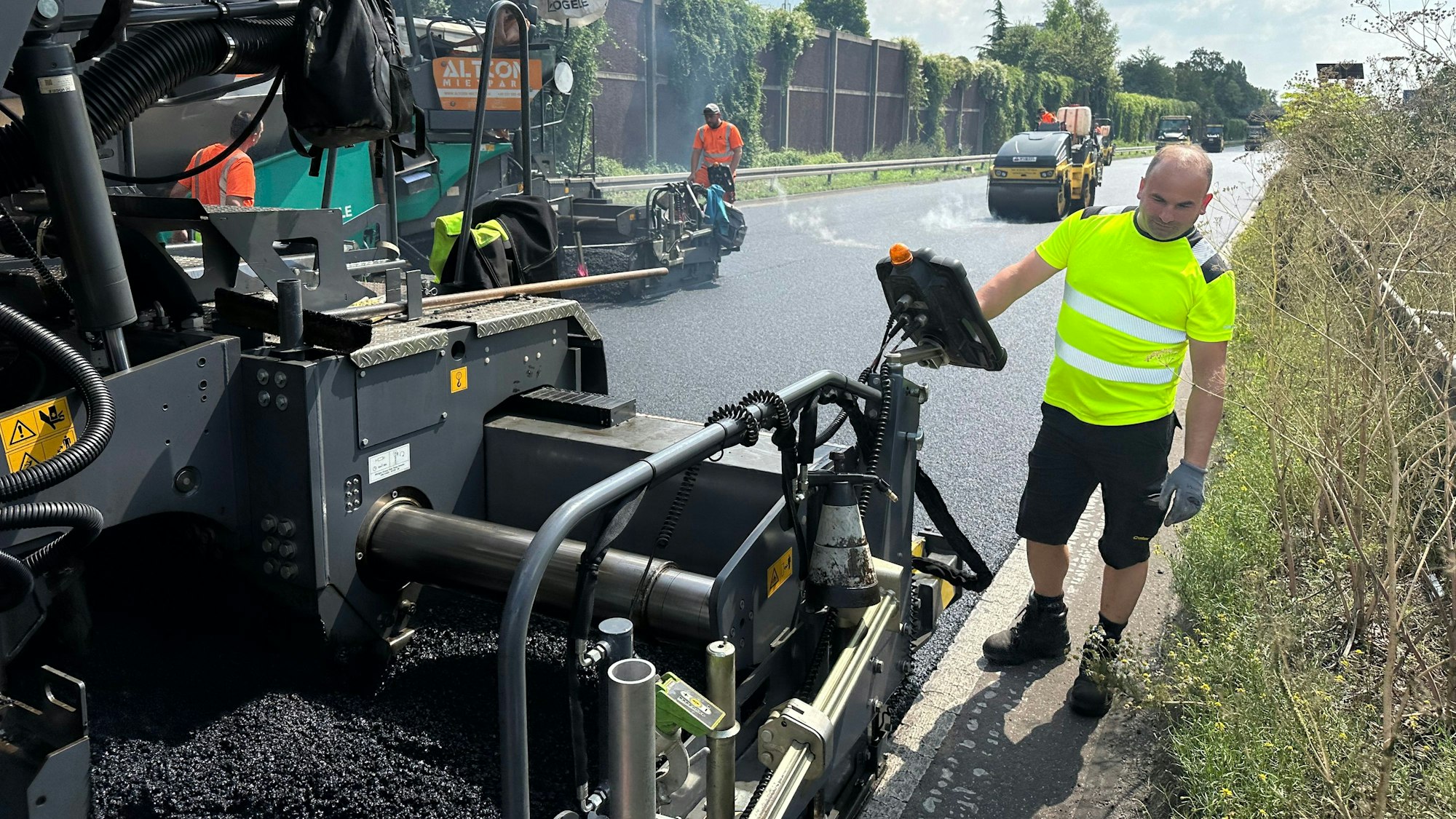 Arbeiter bringen Asphalt auf einer Straße auf.