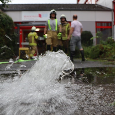 Zu sehen ist ein Wasserschlauch der Feuerwehr vor einem Gebäude. .