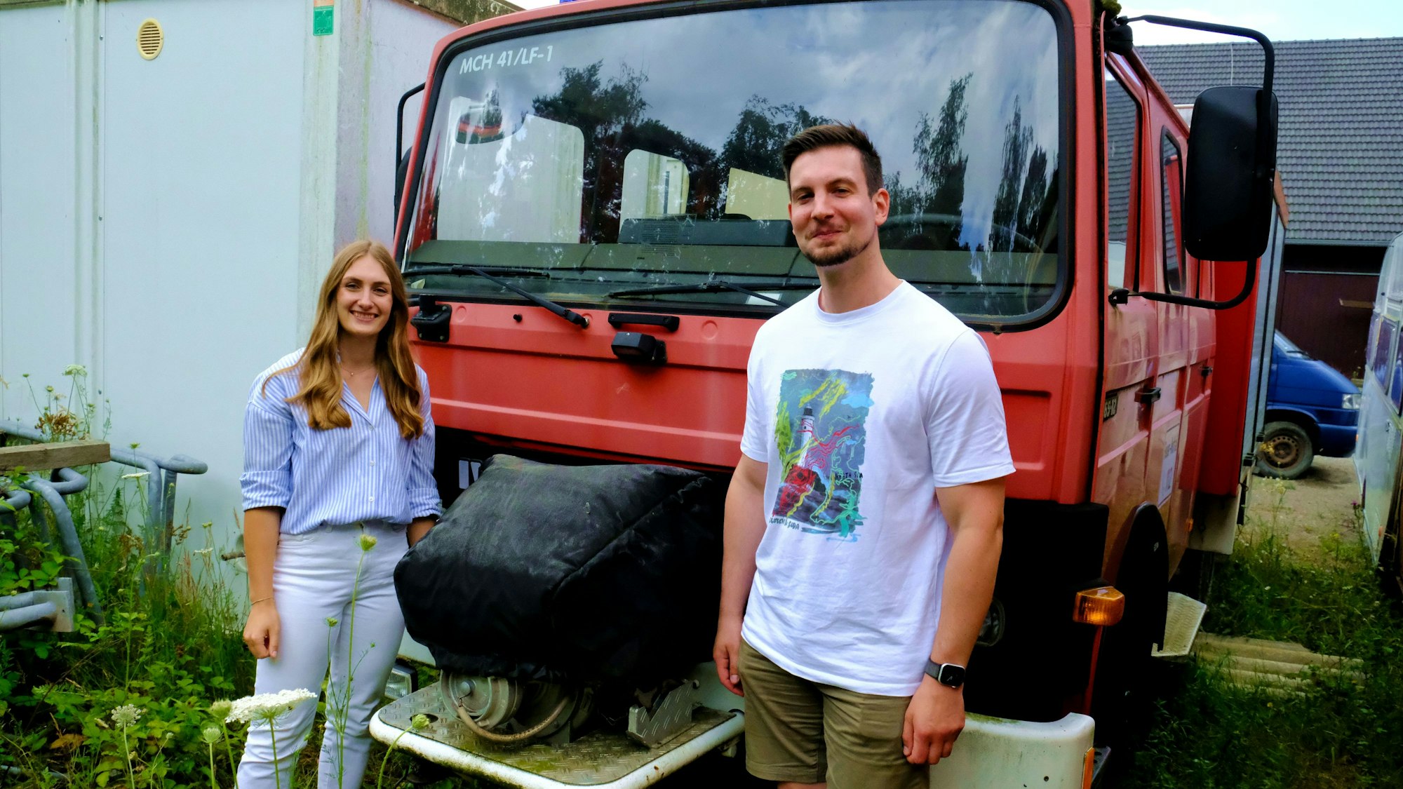 Michelle Klaiber und Jan Clevinghaus stehen vor einem ehemaligen Fahrzeug der Freiwilligen Feuerwehr Mechernich.