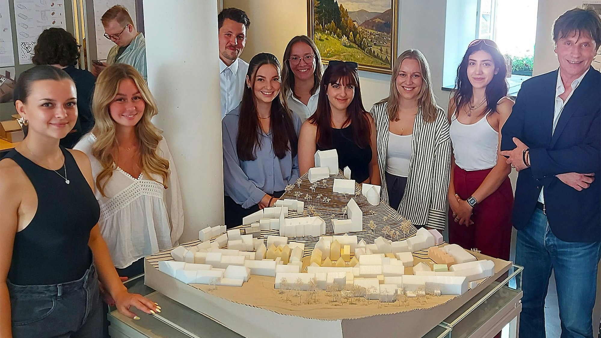 Die Studentinnen und Prof. Georg A. Poensgen stehen hinter und neben dem Modell des Ortskerns.