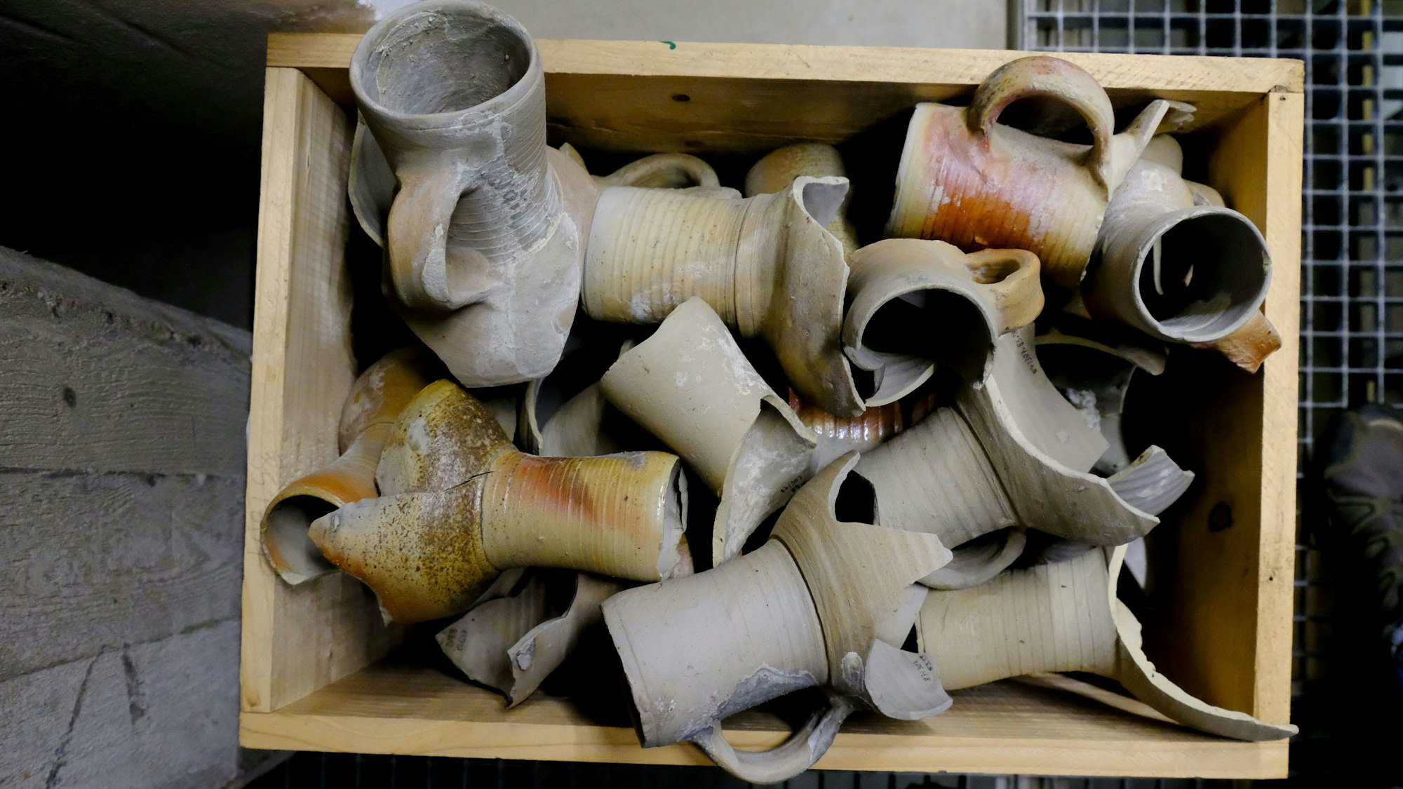 In einer Holzkiste lagern Bruchstücke alter Keramik-Behältnisse.