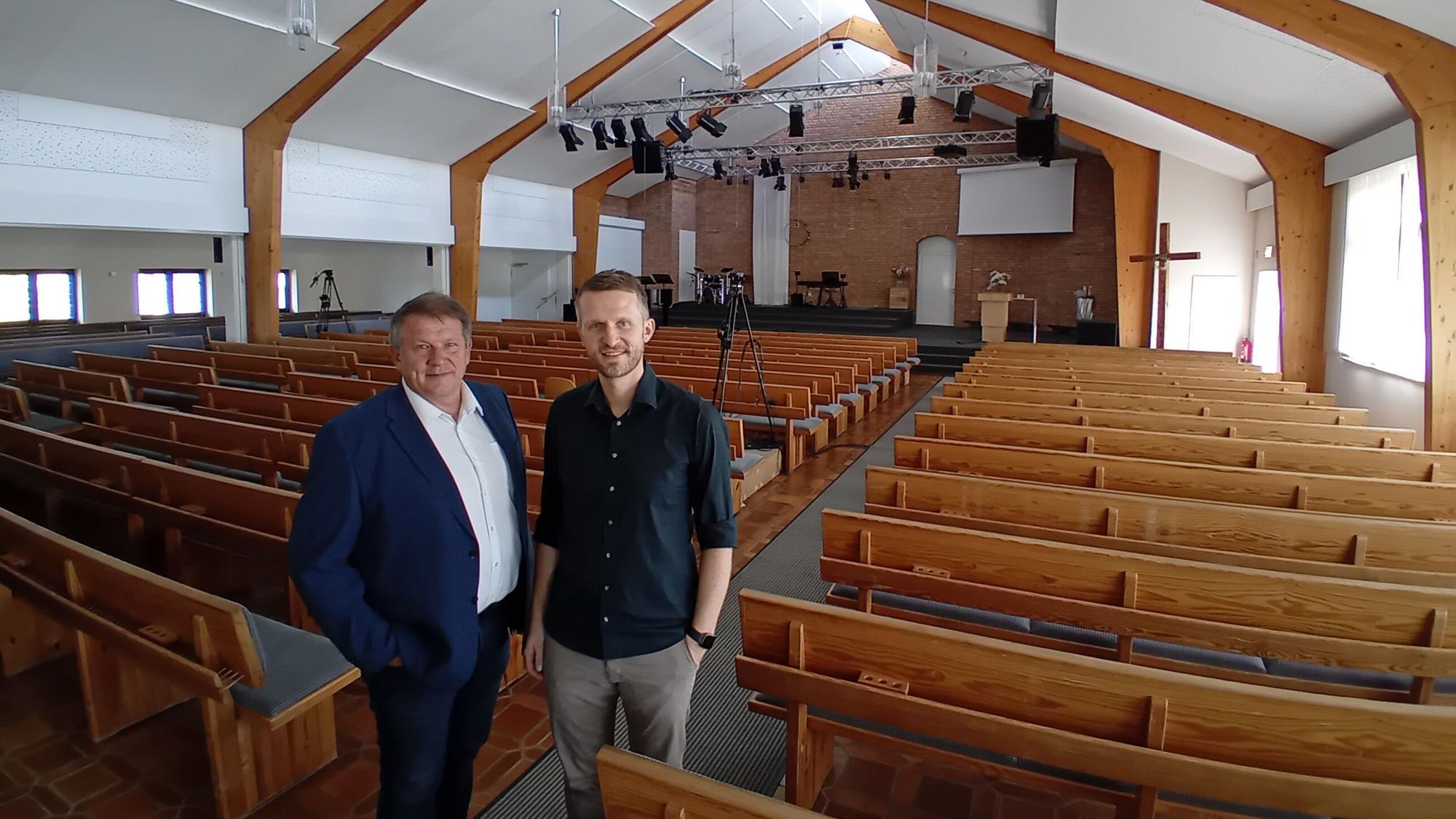 Zwei Männer in einer großen leeren Kirche.