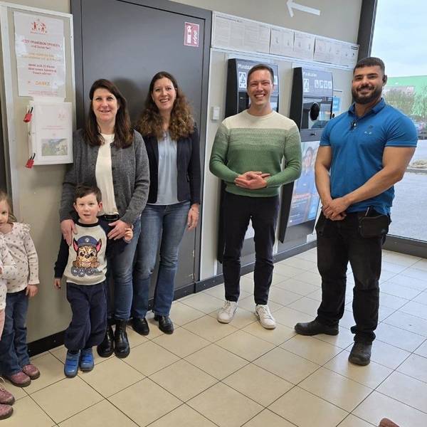 Frauen, Männer und Kinder stehen in einer Aldi-Filiale neben einem Pfandautomaten.