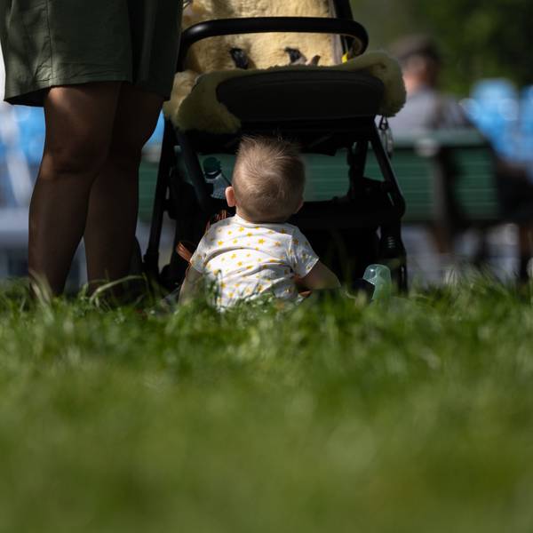 Ein Kind sitzt vor einem Kinderwagen.