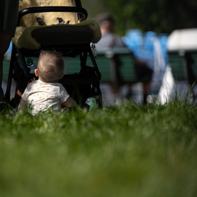 Ein Kind sitzt vor einem Kinderwagen.
