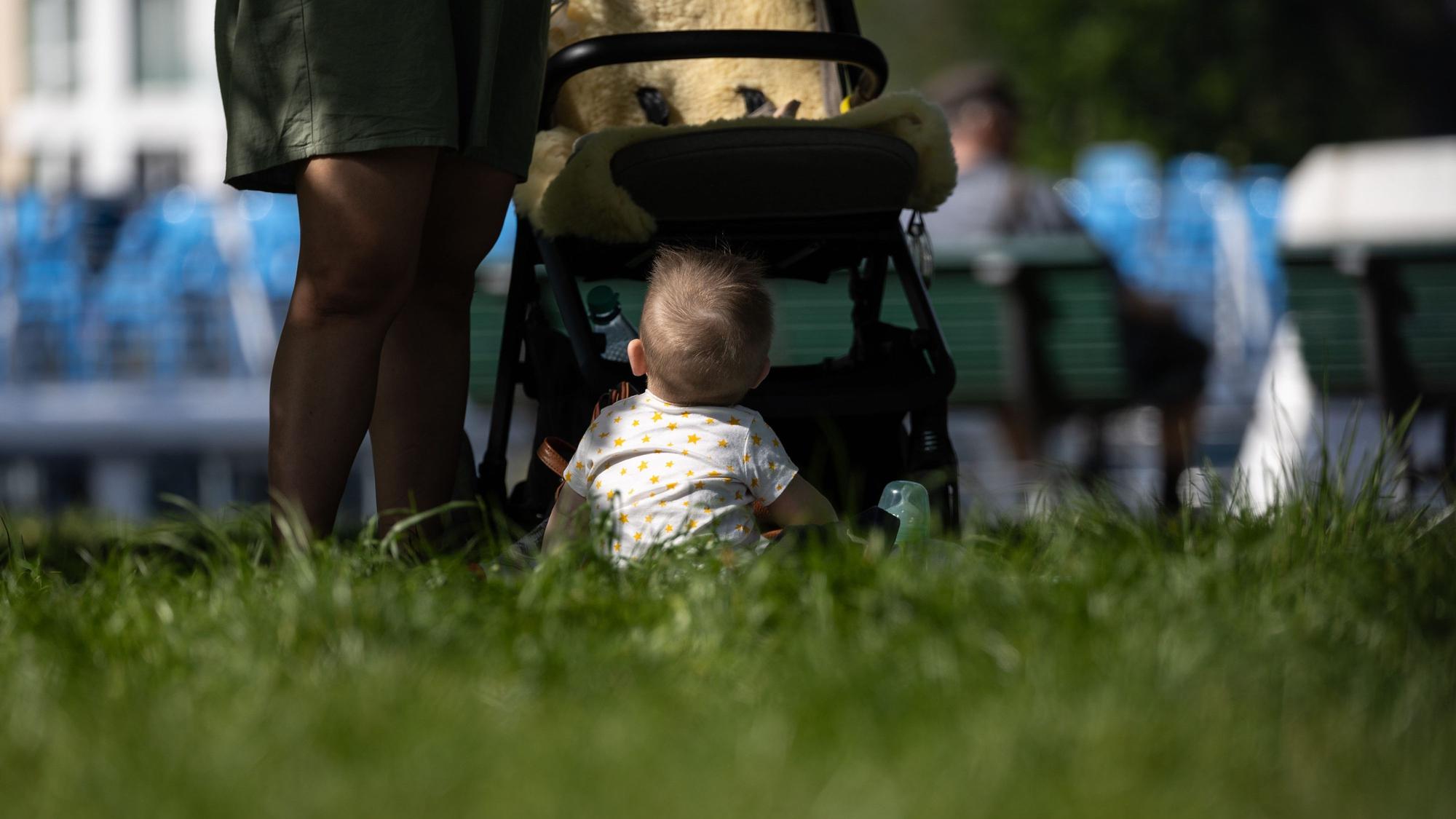 Ein Kind sitzt vor einem Kinderwagen.