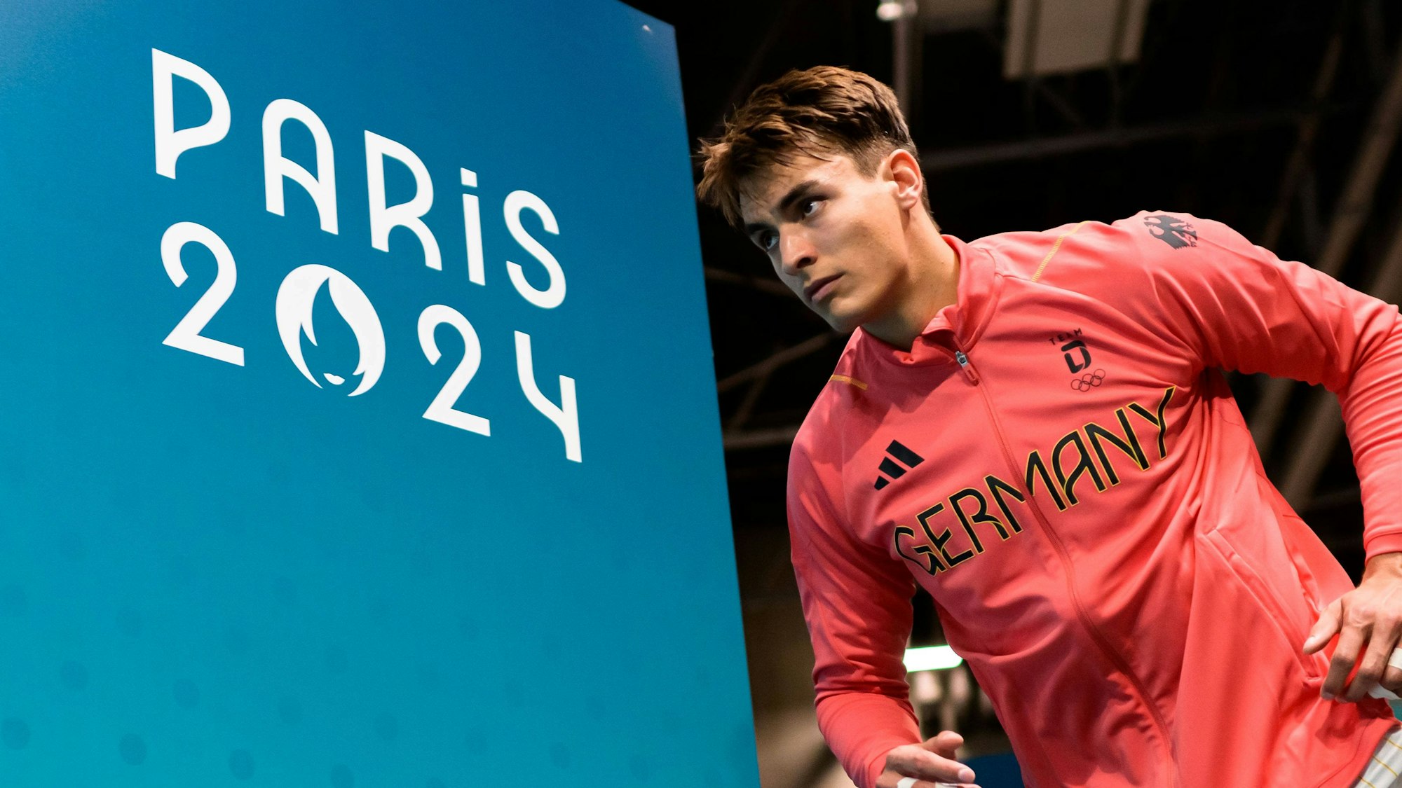 Im Outfit der deutschen Nationalmannschaft läuft Julian Köster vorbei an der Aufschrift Paris 2024 in die Halle ein.