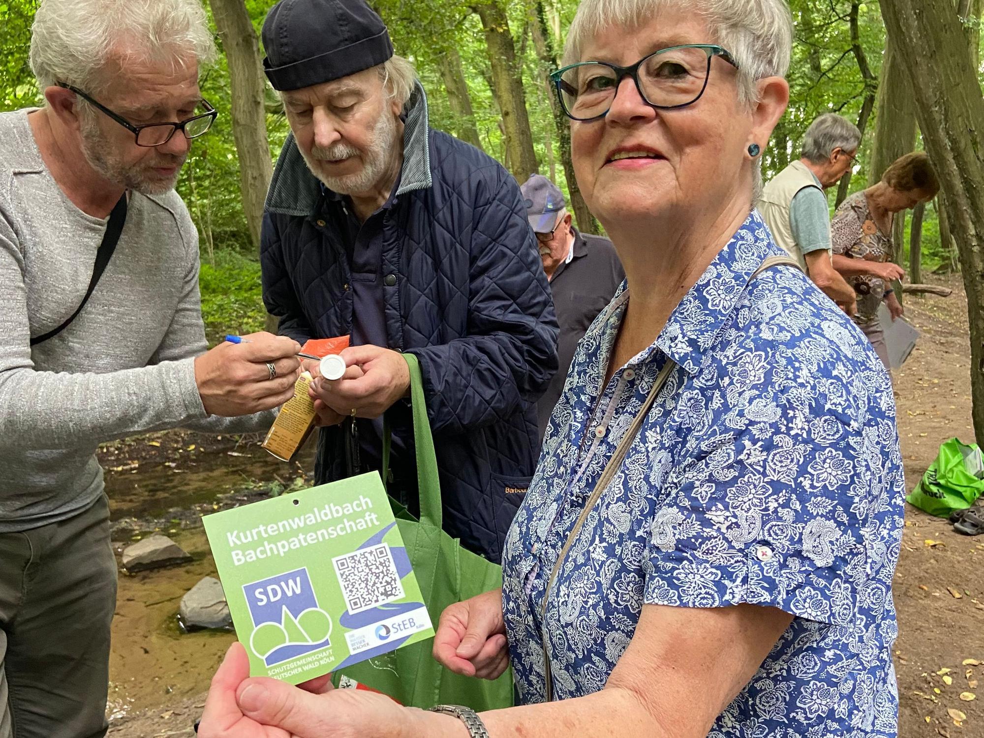 Karin Merten hält ein Schild mit einem QR-Code in der Hand.