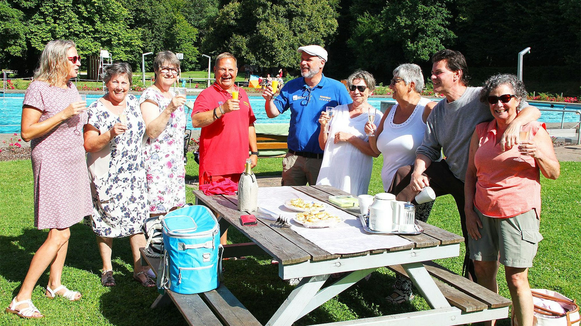 Einige Frauen und Männer haben ein Picknick im Rosenbad in Gemünd aufgebaut und genießen das Freibad-Wetter.
