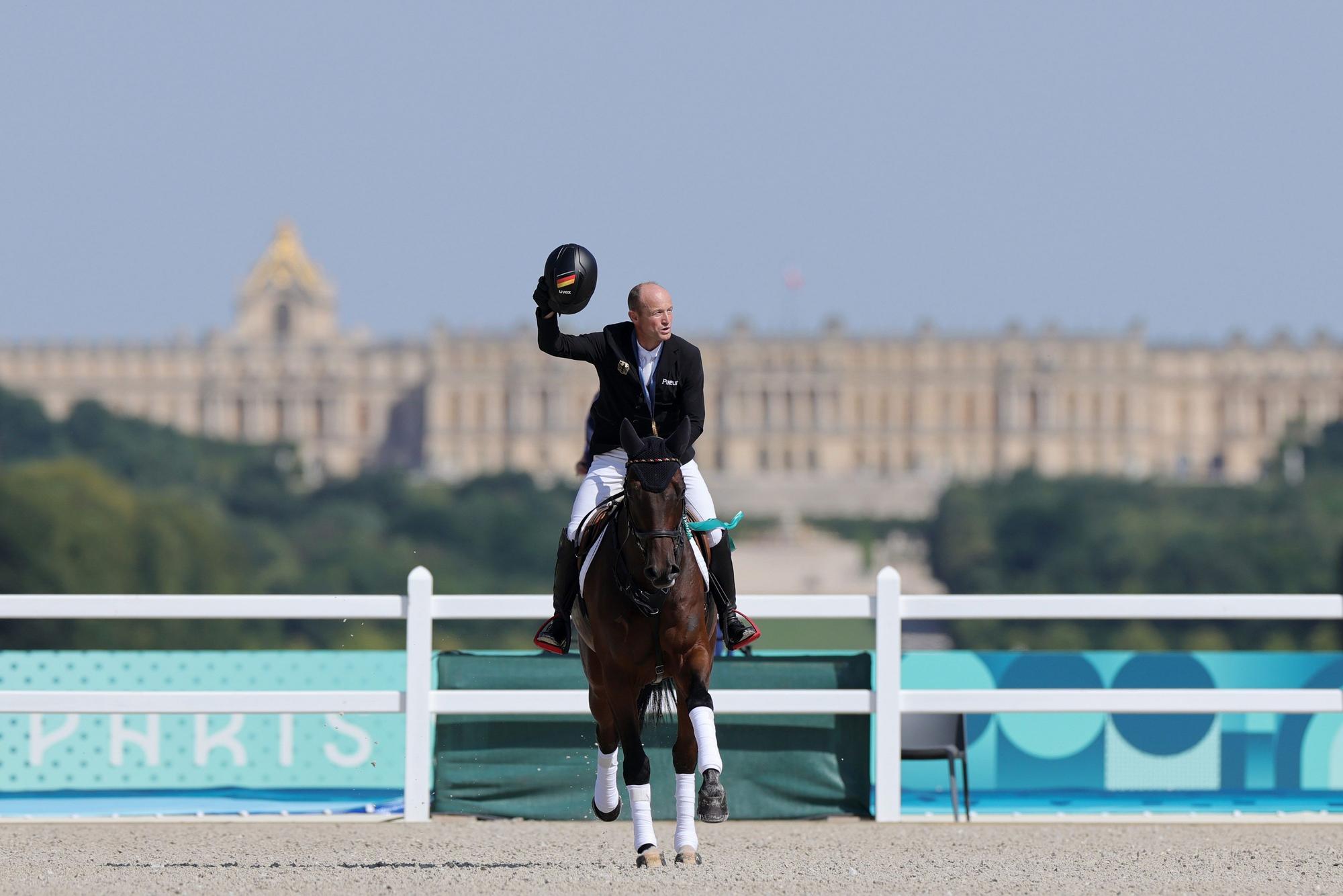 Michael Jung reitet nach der Siegerehrung auf Chipmunk und zeigt seine Goldmedaille.