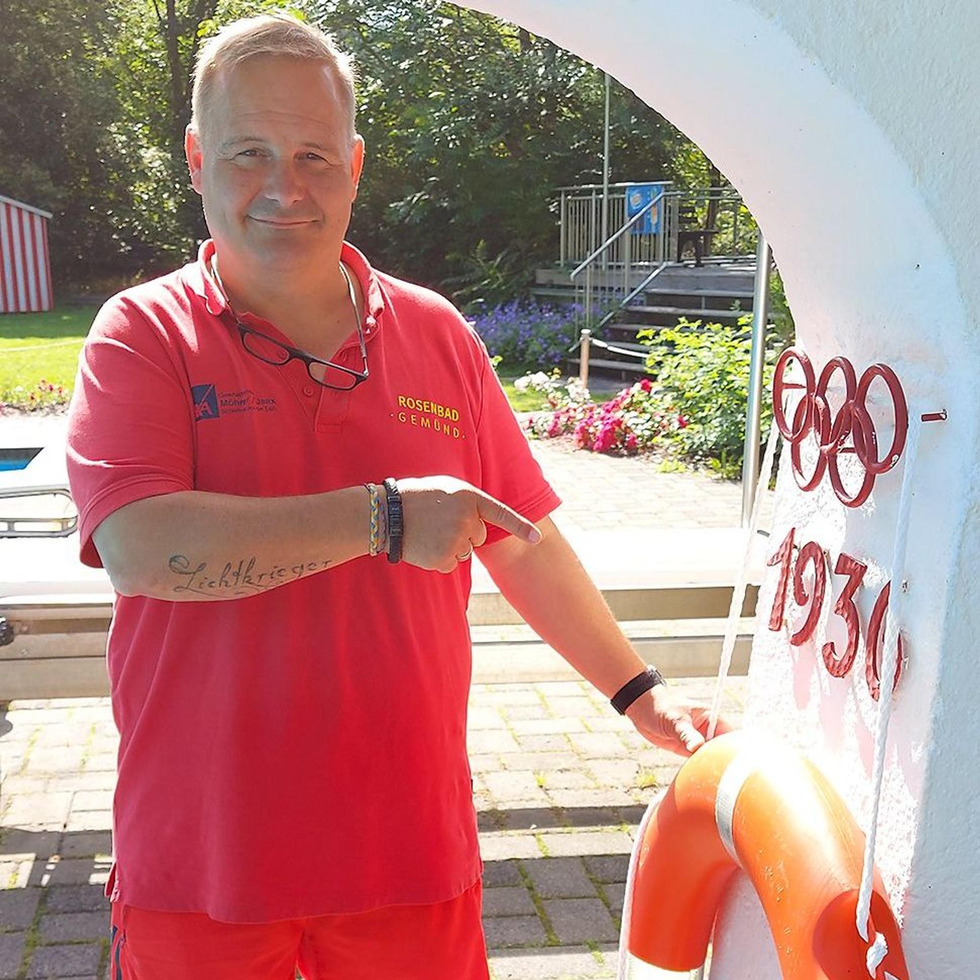 Bademeister Thomas Engelmayer steht im Gemünder Rosenbad am Drei-Meter-Turm und zeigt auf die olympischen Ringe und die Zahl 1936, die auf das Erbauungsjahr hinweisen.