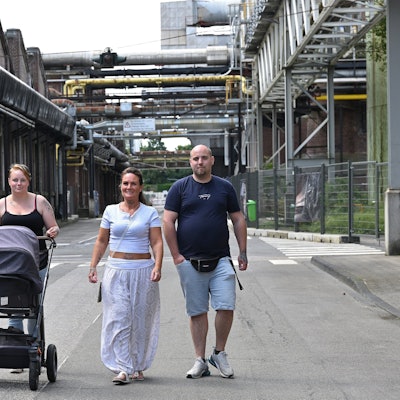 Drei Menschen laufen über das Zanders-Geläne, eine Frau schiebt einen Kinderwagen.