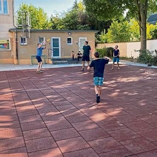 Jugendlich beim Ballspielen auf einem Schulhof.