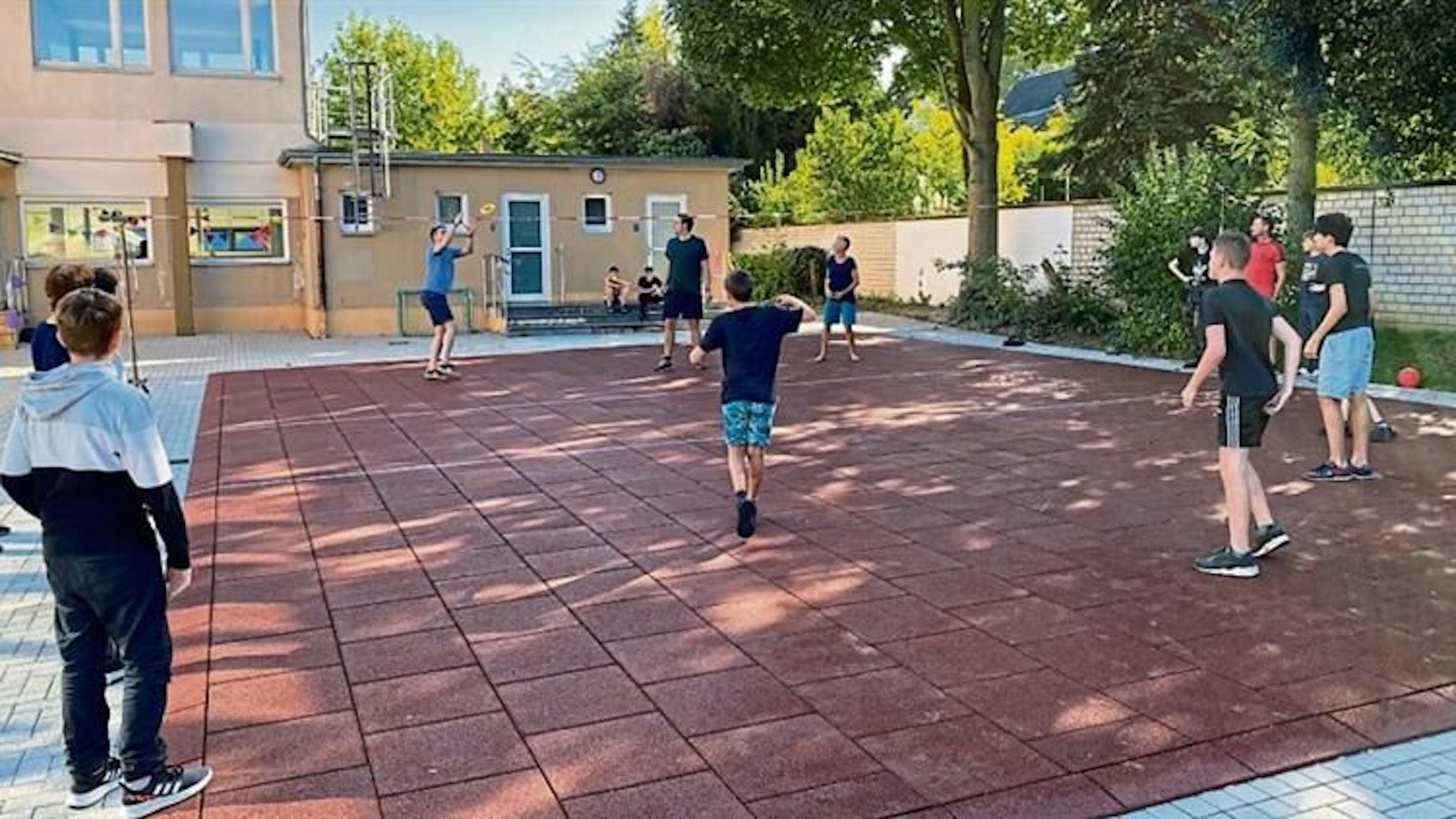 Jugendlich beim Ballspielen auf einem Schulhof.