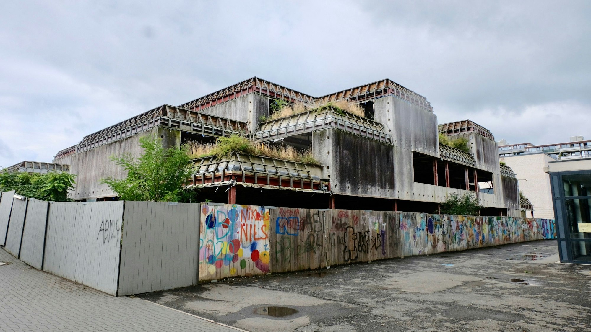 Hinter dem bunt bemalten Bretterzaun wartet das ehemalige Schulgebäude des Georg-Büchner-Gymnasiums auf den Abriss.