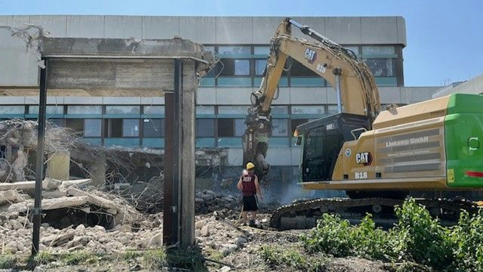 Ein Abrissbagger vor einem alten Schulgebäude aus den 70er Jahren.