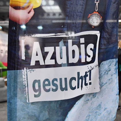 „Azubis gesucht“ steht auf einem Banner bei einer Berufsorientierungsmesse.