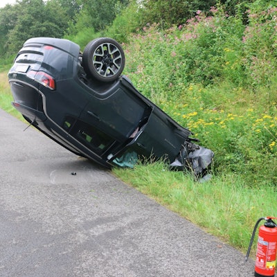 Ein Auto liegt auf einem Standstreifen einer Autobahn auf dem Dach.