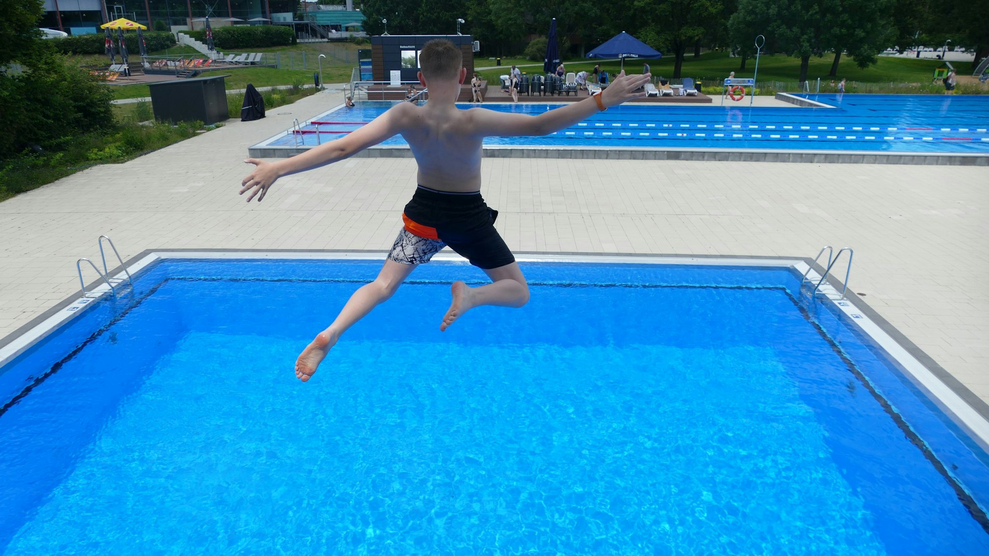 Ein Junge springt ins Becken.
