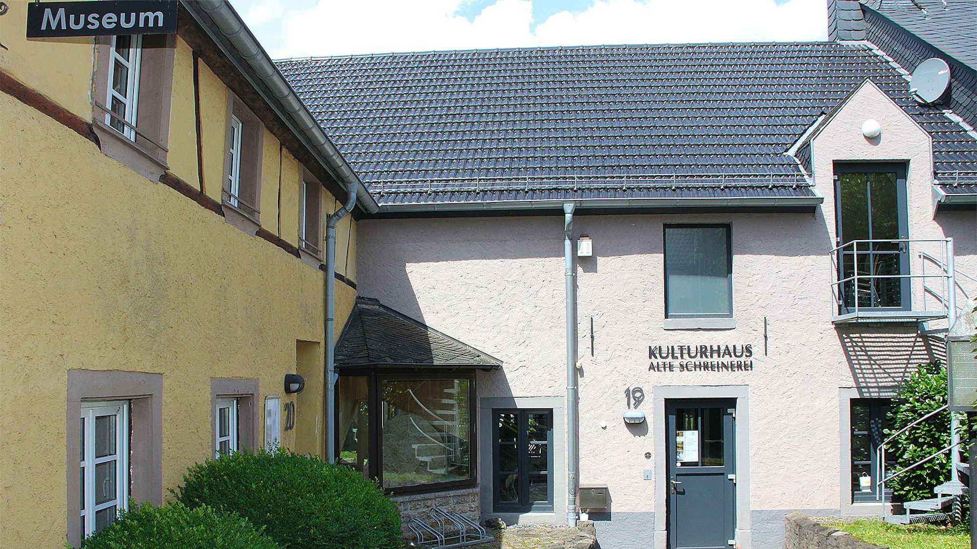 Frontal ist das Kulturhaus in der alten Schreinerei in Hillesheim zu sehen, links das gelb angestrichene Haus, dessen künftige Nutzung noch unklar ist.