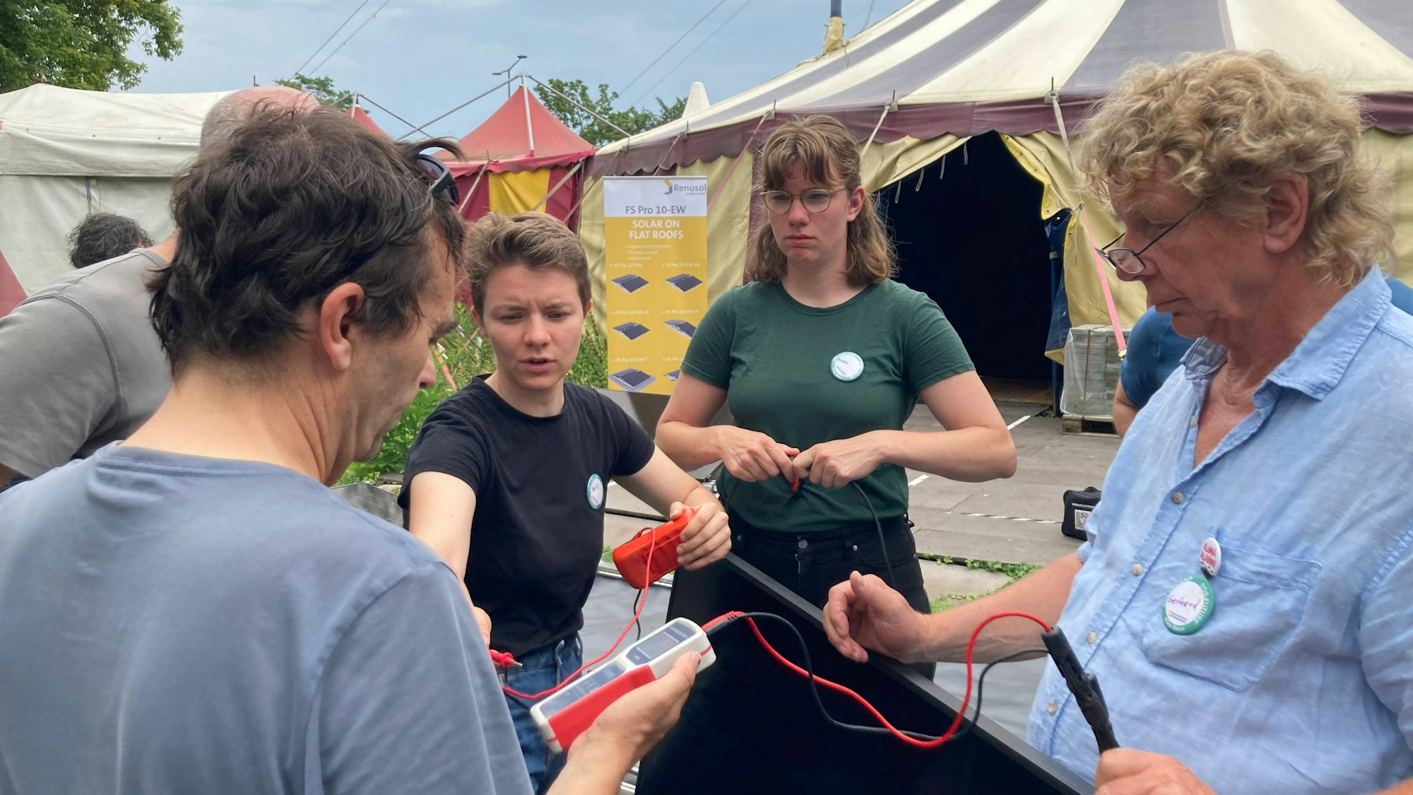 Beccy Reuschenberg (3. v. rechts) schließt ein Messgerät an ein PV-Modul an.