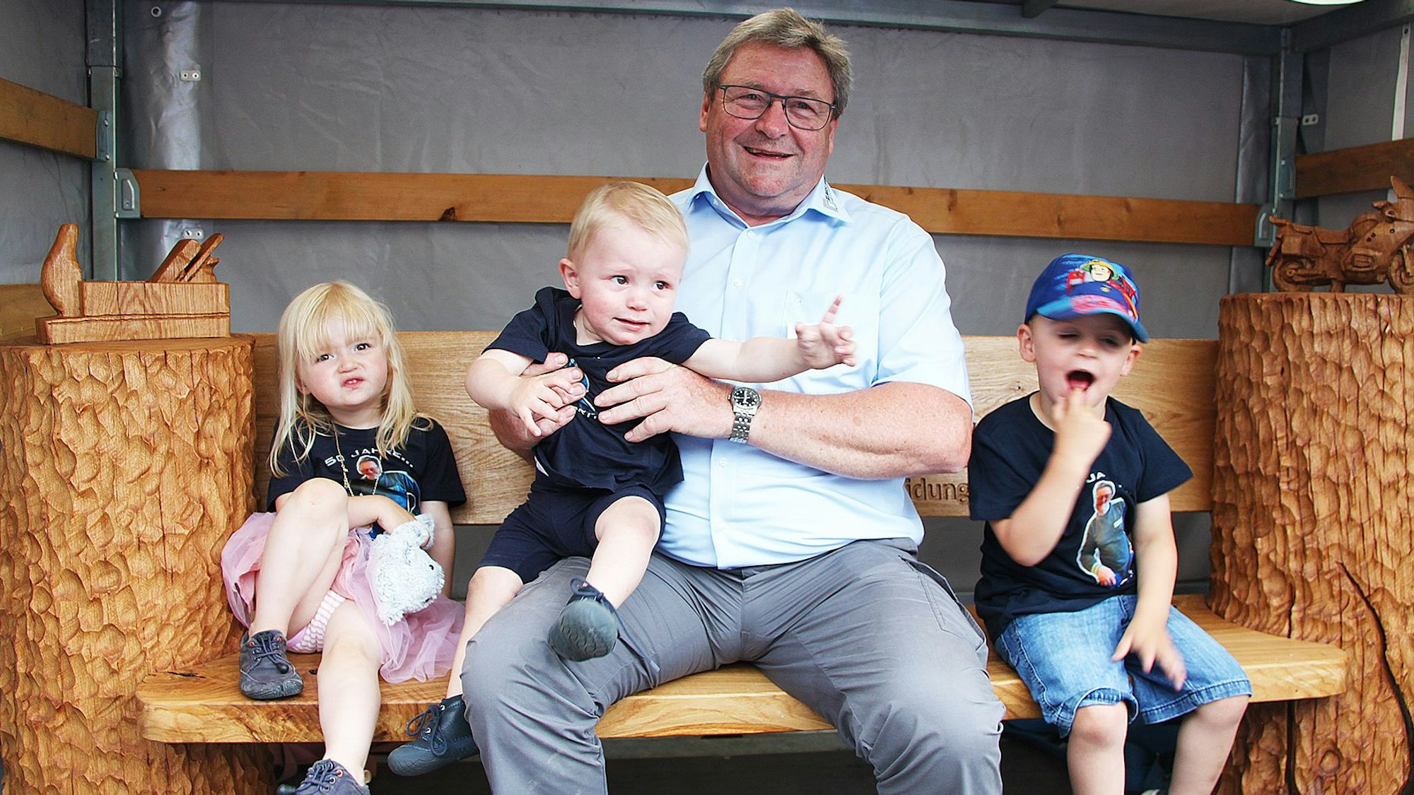 Axel Keul sitzt mit seinen drei Enkelkindern auf einer Bank.