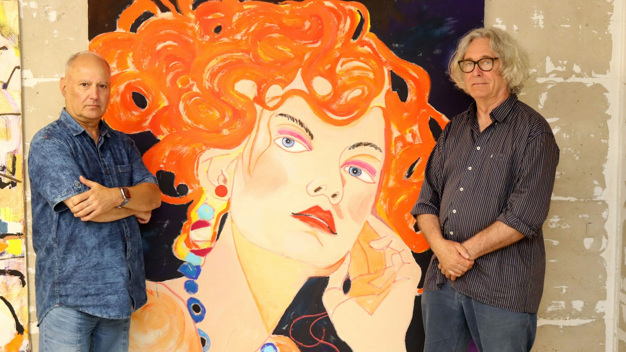 Hermann-Josef Gemünd steht mit verschränkten Armen neben einem Porträt einer Frau mit knallroten Haaren. Auf der anderen Seite steht Kurator Jürgen Roder.