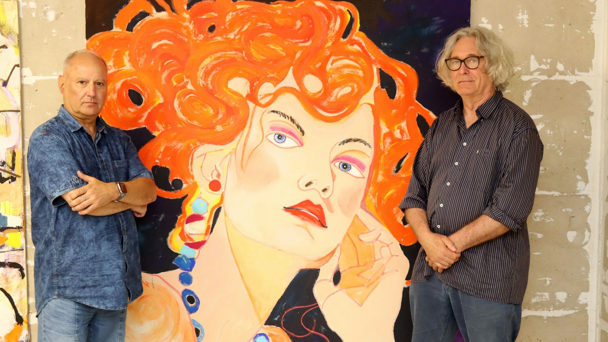 Hermann-Josef Gemünd steht mit verschränkten Armen neben einem Porträt einer Frau mit knallroten Haaren. Auf der anderen Seite steht Kurator Jürgen Roder.