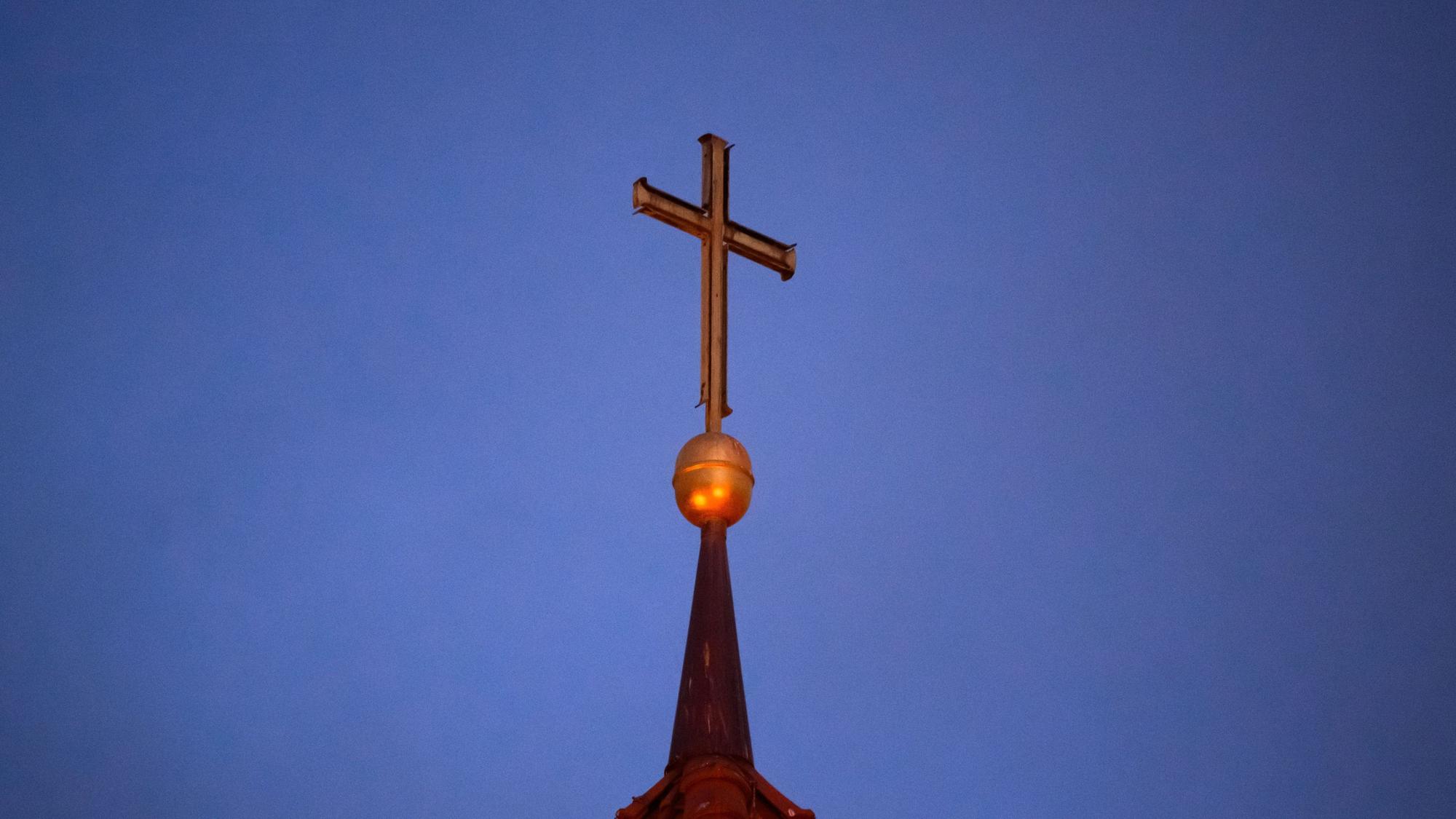 Ein Kreuz steht auf der Kirchturmspitze