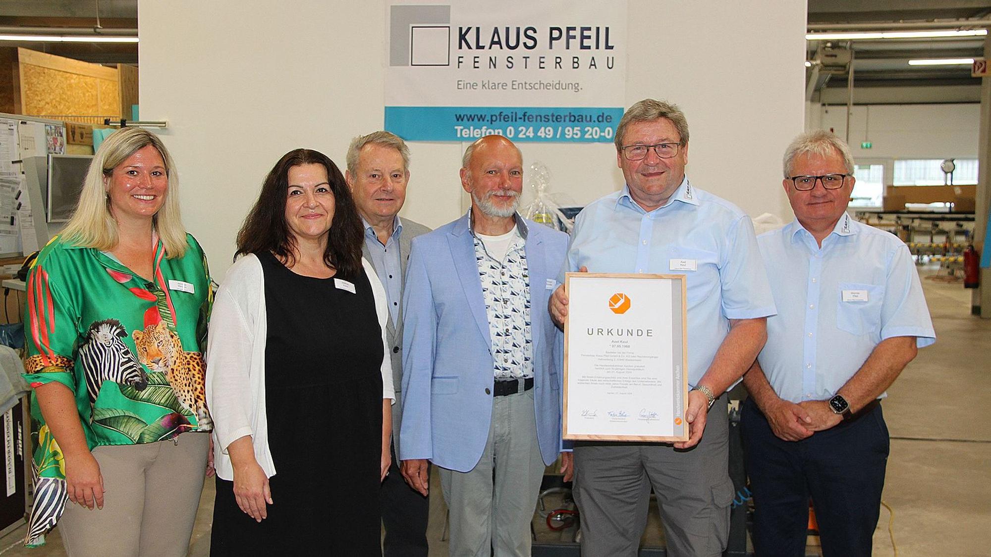 Axel Keul hält seine Urkunde in der Hand und ist von Gratulanten umgeben,