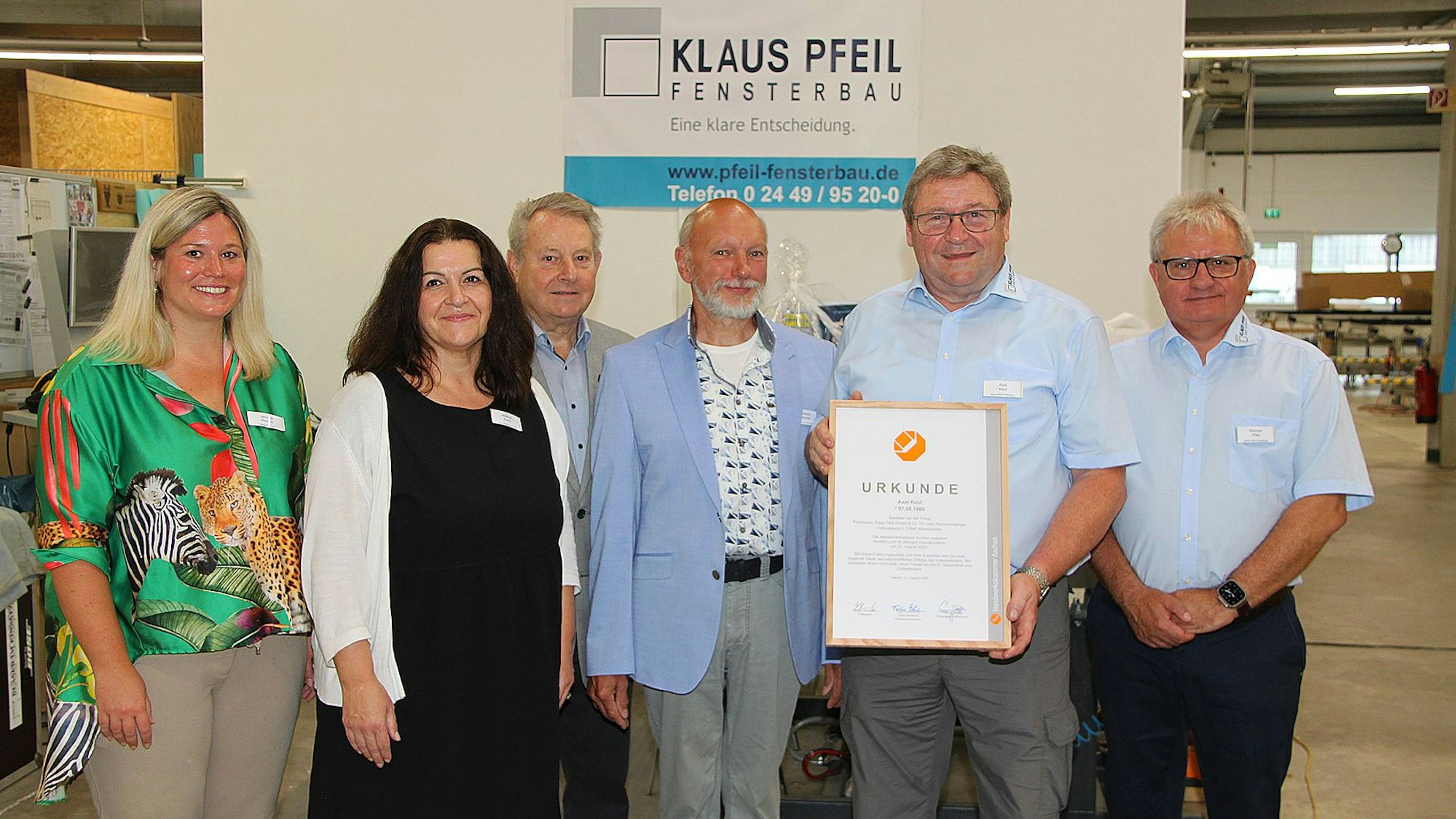 Axel Keul hält seine Urkunde in der Hand und ist von Gratulanten umgeben,
