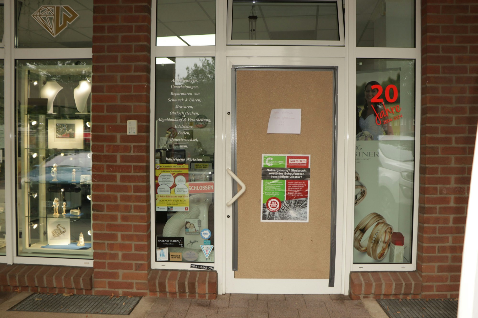 Das Bild zeigt die Eingangstür eines Juweliergeschäfts, die mit einer Holzplatte notdürftig repariert wurde.