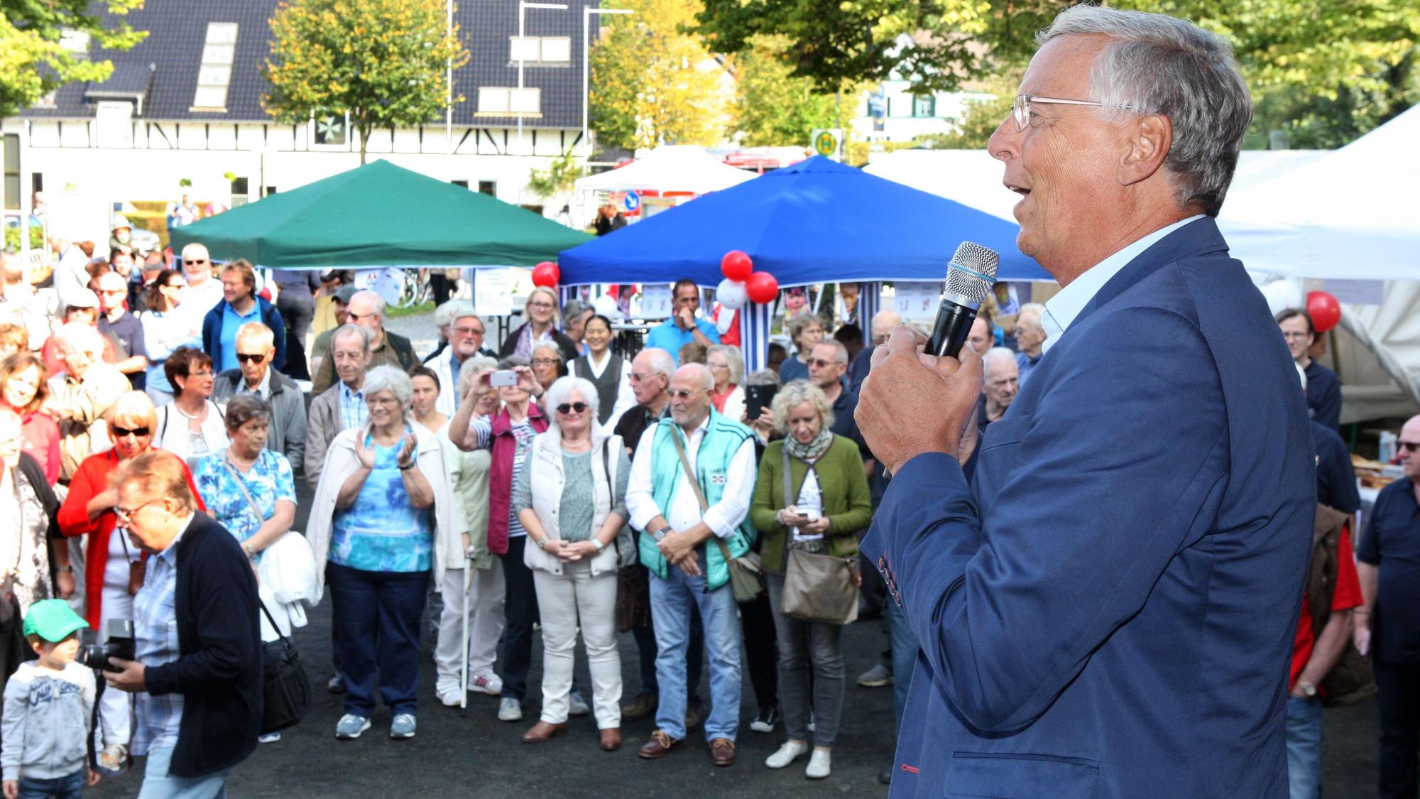 Schirmherr Wolfgang Bosbach spricht mit einem Mikro zu Gästen bei der Eröffnung des 1. Strundetal-Festes 2017 in Herrenstrunden.
