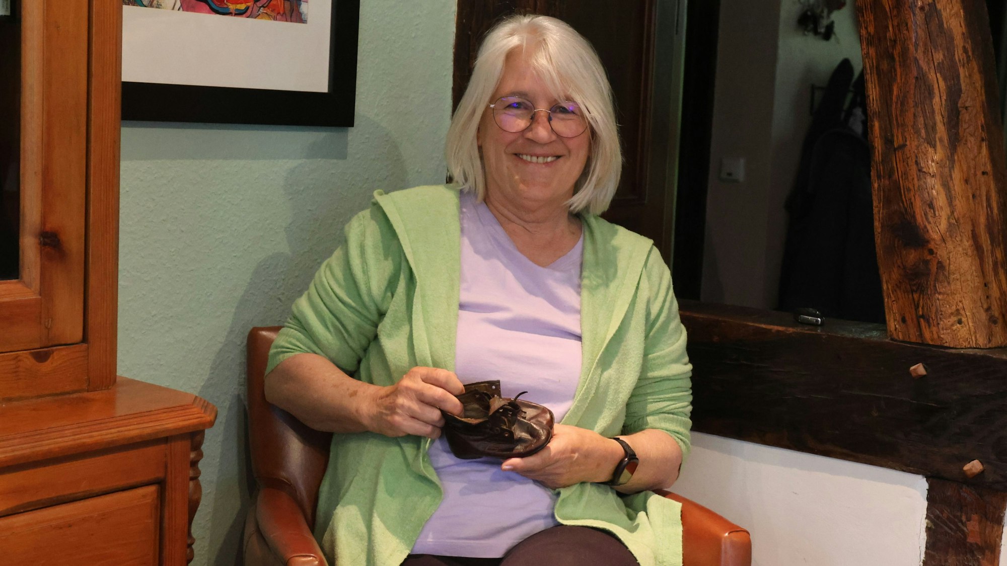 Hannelore Förster hält zwei kleine Kinderschuhe in den Händen.