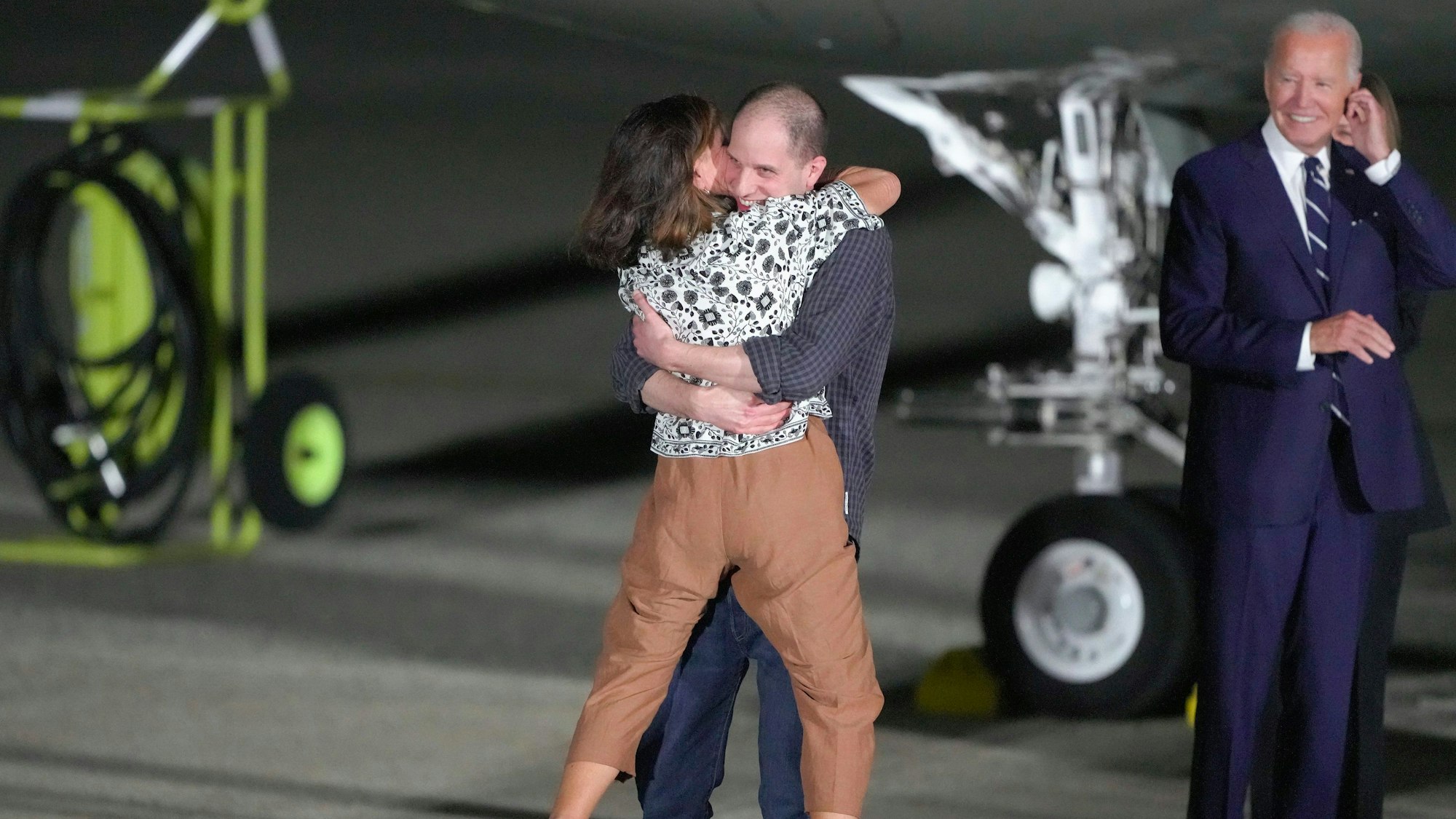 Evan Gershkovich umarmt auf dem Flugfeld der Andrews Airforce Base seine Mutter Ella Milman. US-Präsident Joe Biden grinst im Hintergrund.