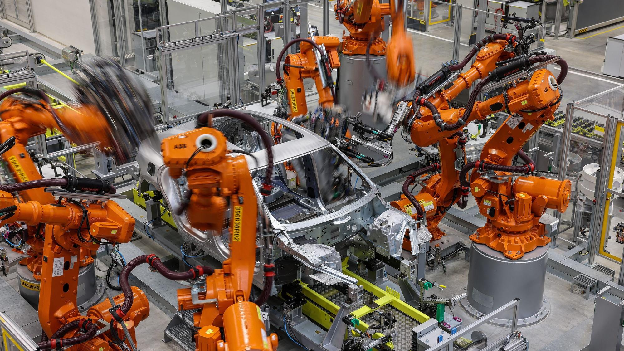 , Leipzig: Industrieroboter arbeiten an der Karosserie für einen vollelektrischen Porsche Macan im Werk Leipzig.