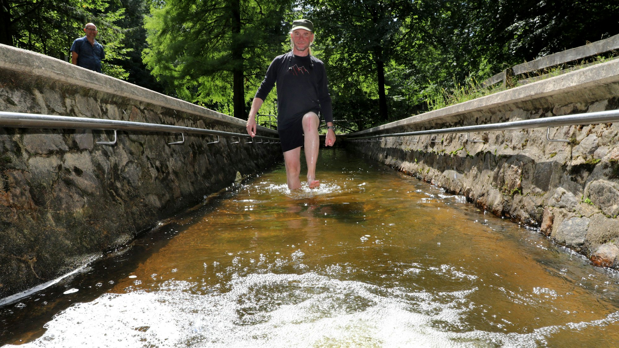 Ein Mann geht durch das Tretbecken der Wassertretstelle im Königsforst.
