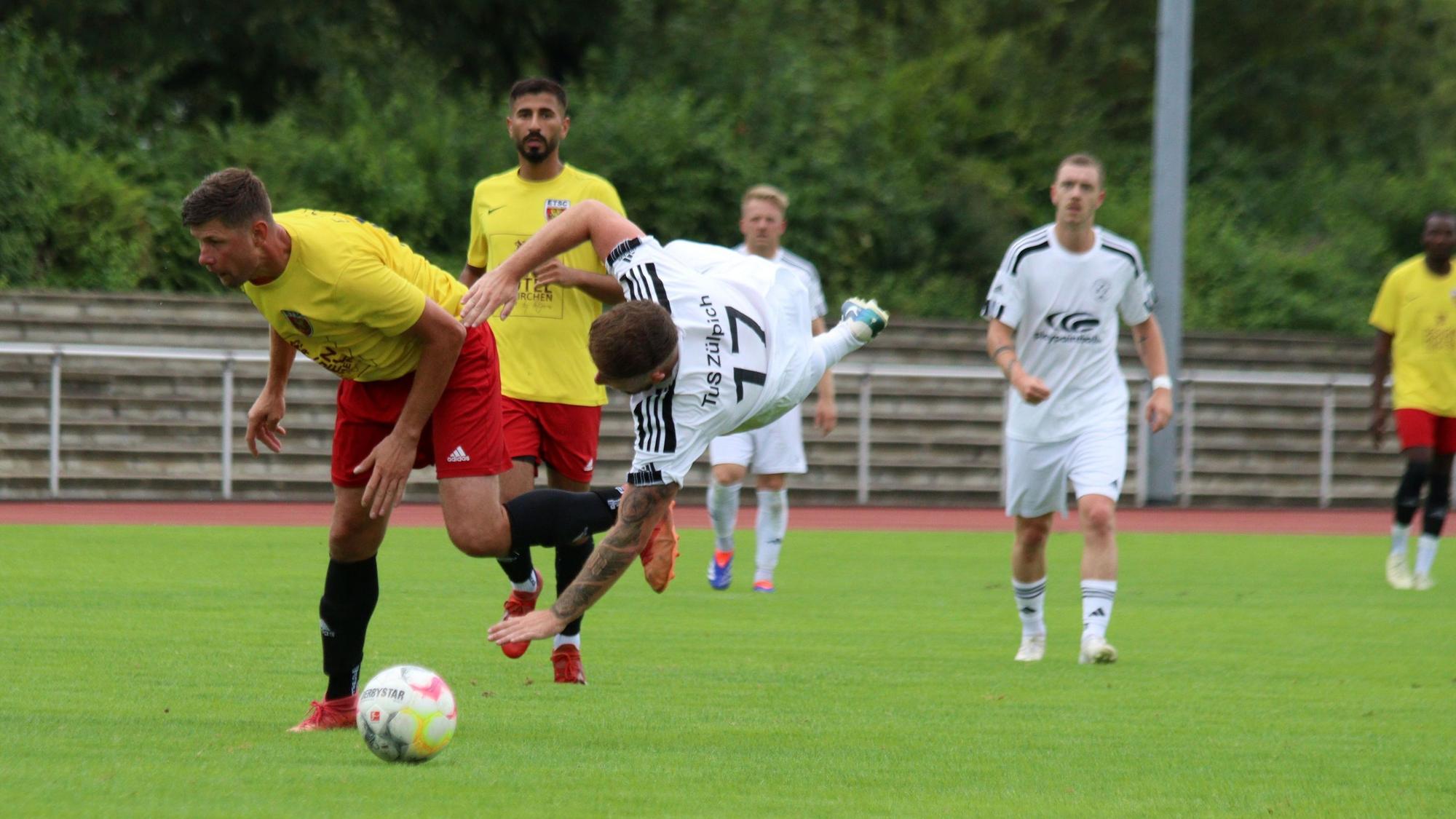 Ein Fußballspieler steht quer in der Luft, nachdem er mit einem Gegenspieler zusammengeprallt ist.