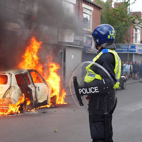 Ein Polizist blickt auf ein brennendes Auto auf der Parliament Road während einer Anti-Einwanderungsdemonstration.