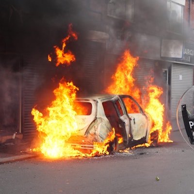 Ein Polizist blickt auf ein brennendes Auto auf der Parliament Road während einer Anti-Einwanderungsdemonstration.