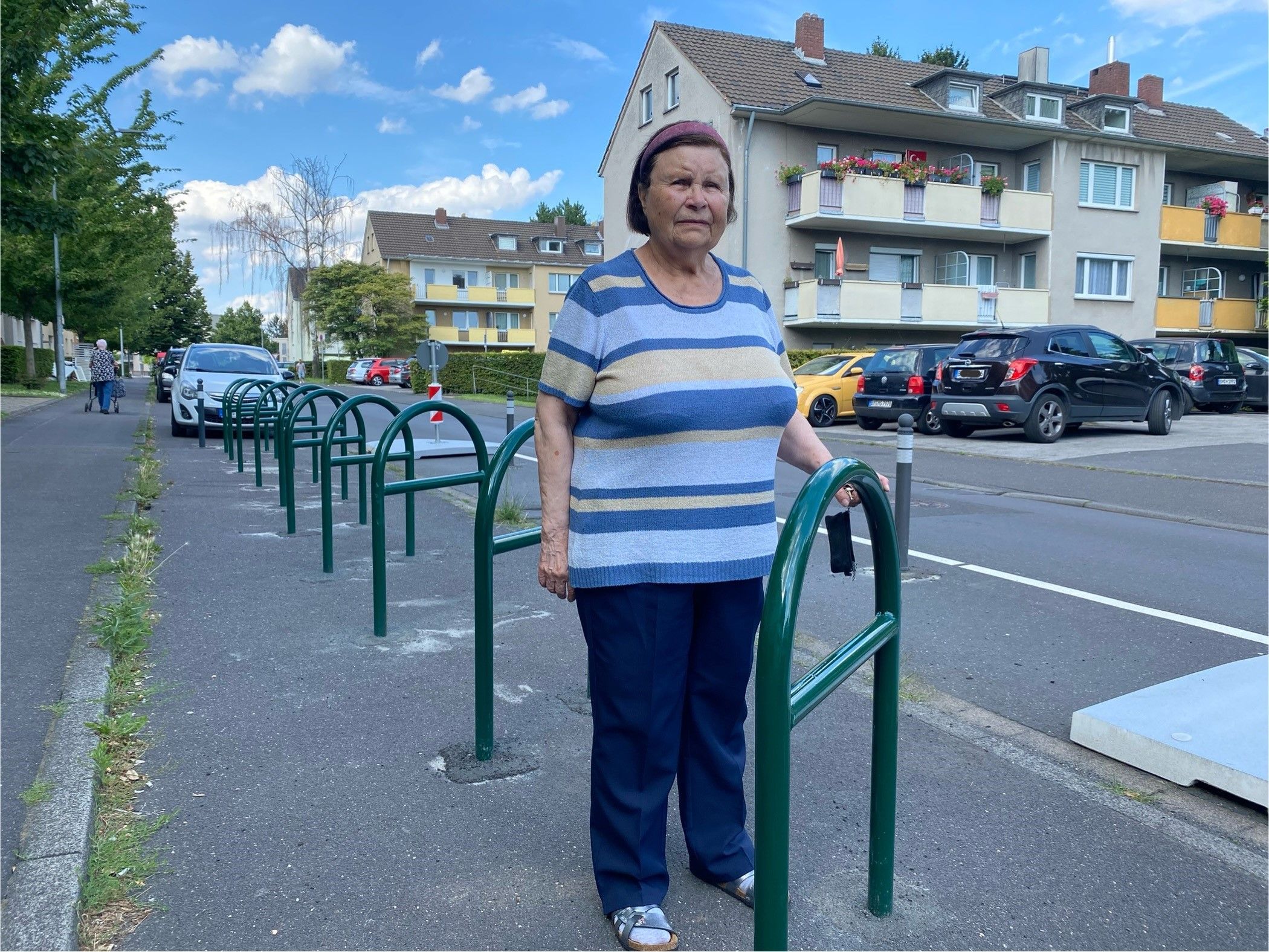 Auf dem Foto ist Marianne Hermann aus Brühl zu sehen. Sie steht zwischen den Metallbügeln, an denen Fahrräder abgestellt werden sollen. Aber kein einziges Rad steht dort.