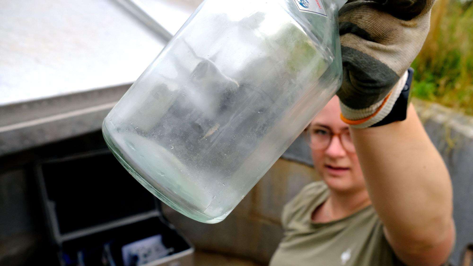 Lea Garmer zeigt eine der Sickerwasserproben in einer Glasflasche.