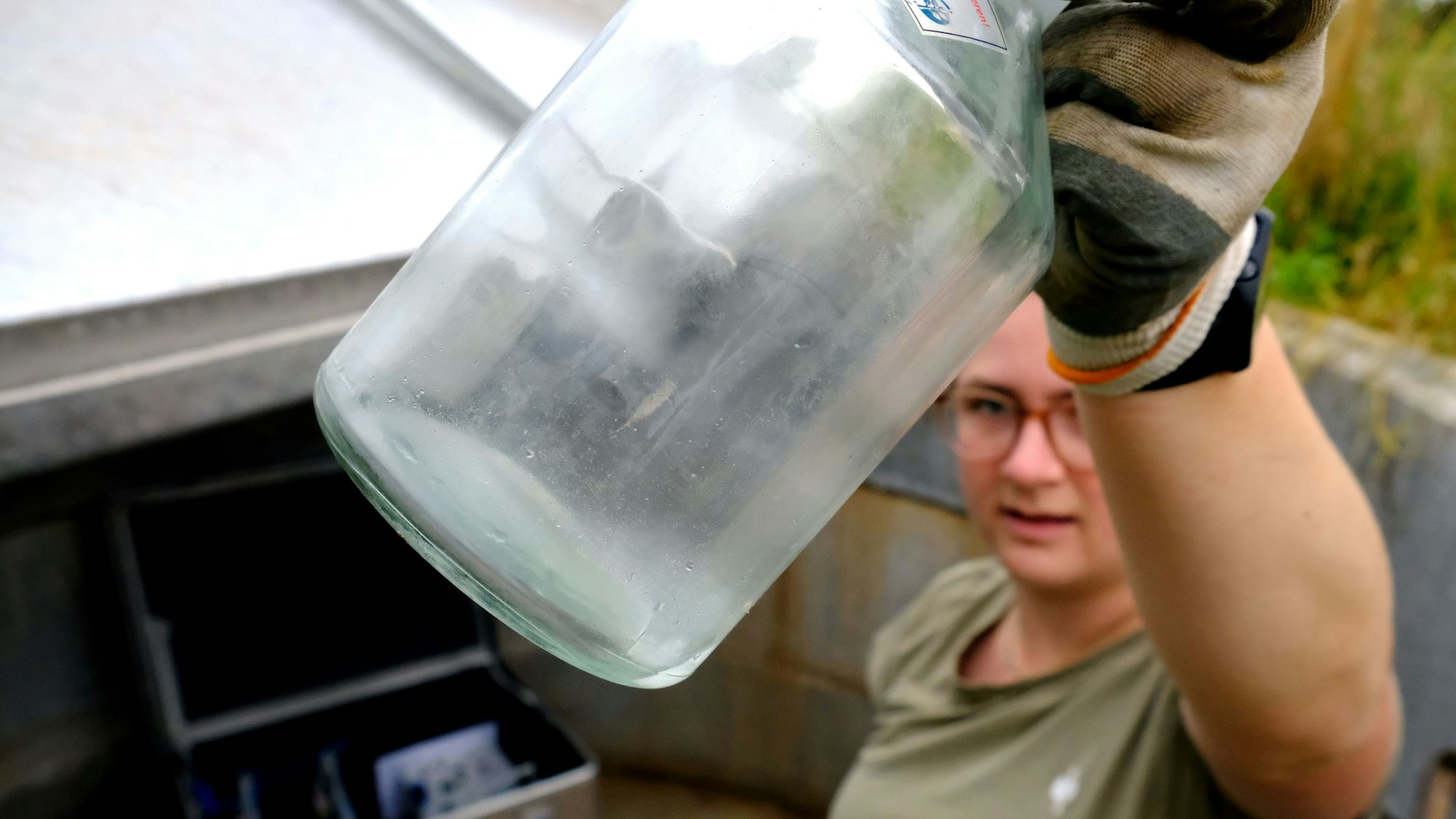 Lea Garmer zeigt eine der Sickerwasserproben in einer Glasflasche.