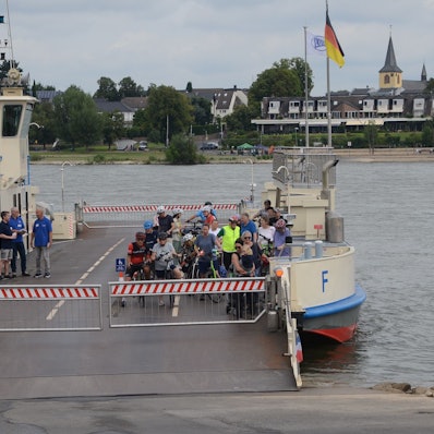 Eine Rheinfähre legt an. An Bord sind nur Radfahrer.