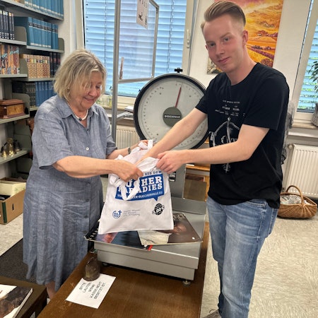 Gisela Lindner wiegt die Bücher, die Lehramtsstudent Jonathan Jungbluth gerade ausgesucht hat.