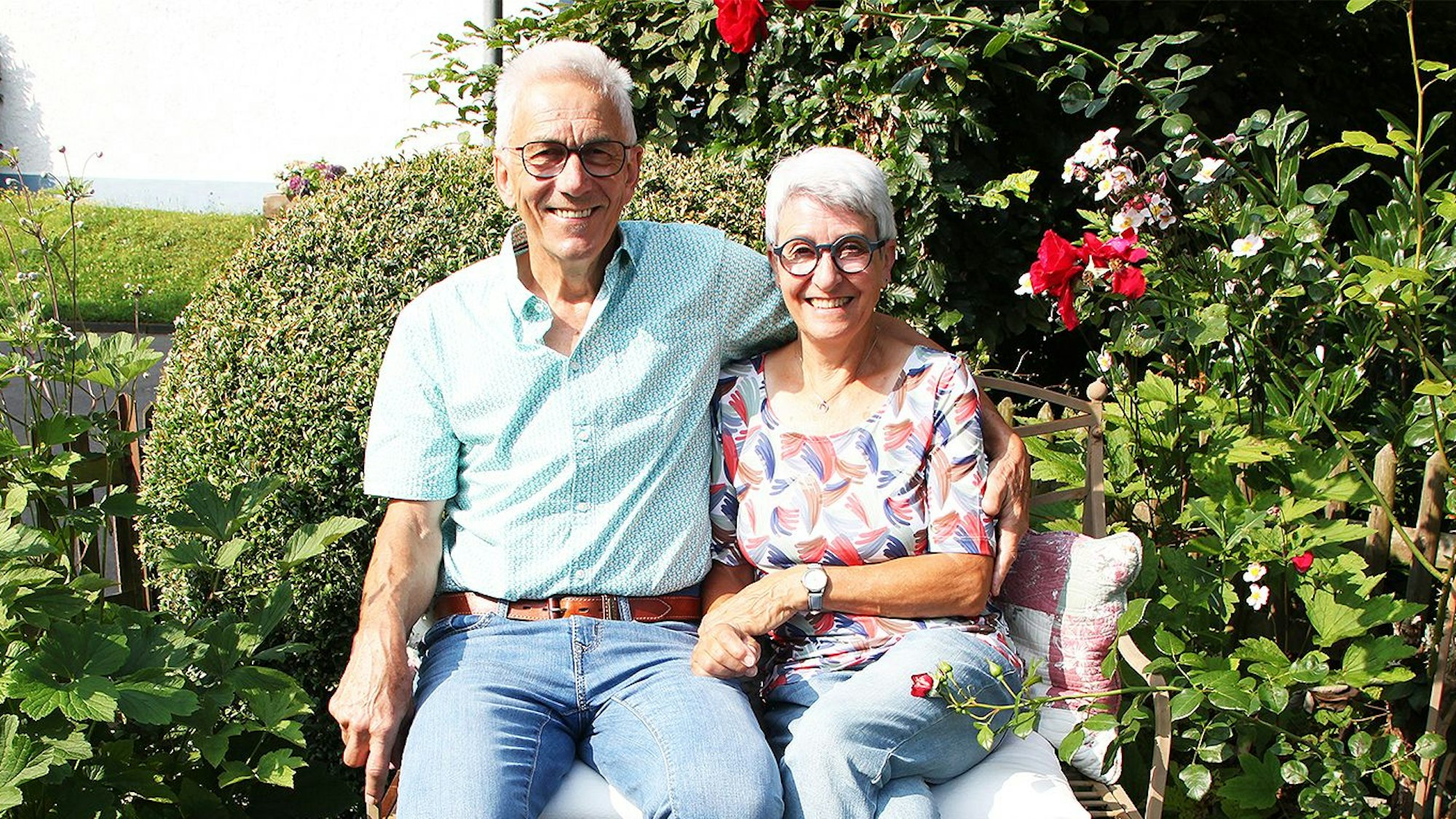 Jutta und Heinz-Anton Schneider sitzen nebeneinander auf einer Bank im Garten.
