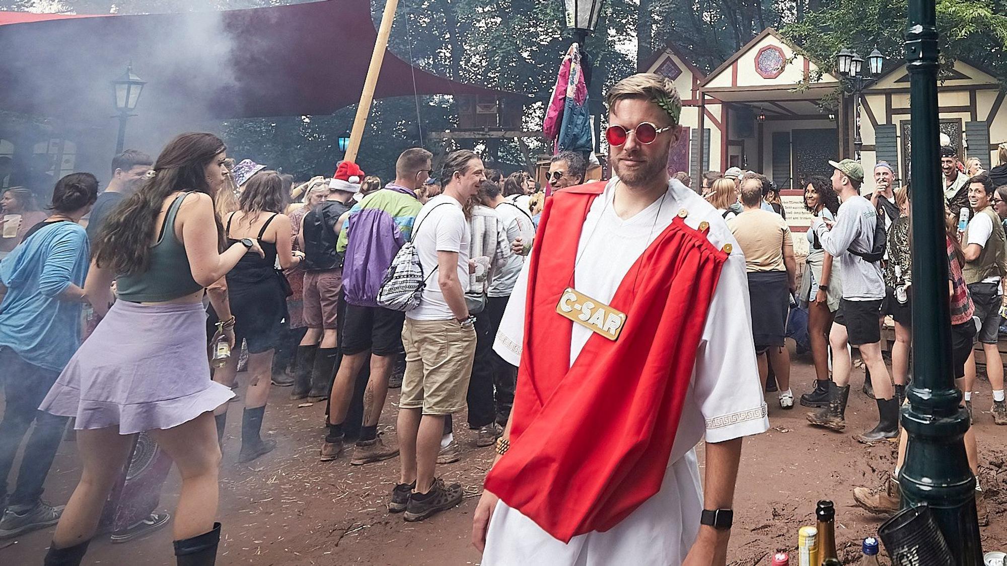 Ein Besucher des Zugvögel-Festivals hat eine Art römischer Toga und eine Sonnenbrille mit roten Gläsern angezogen.