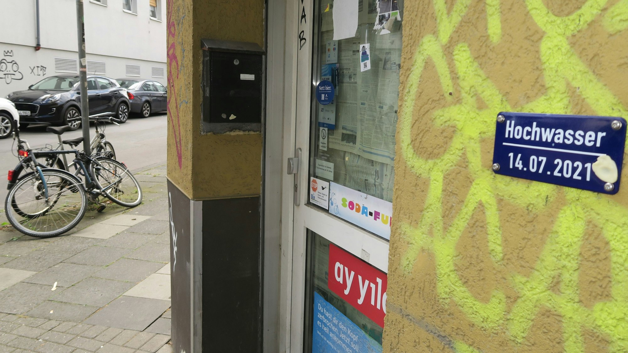 Blick auf eine Plakette an einer mit Graffiti beschmierten Hauswand.